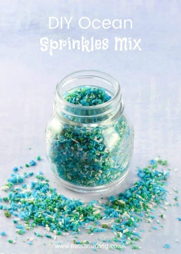 Blue ocean mix homemade coconut sprinkles in a glass jar with sprinkles scattered around