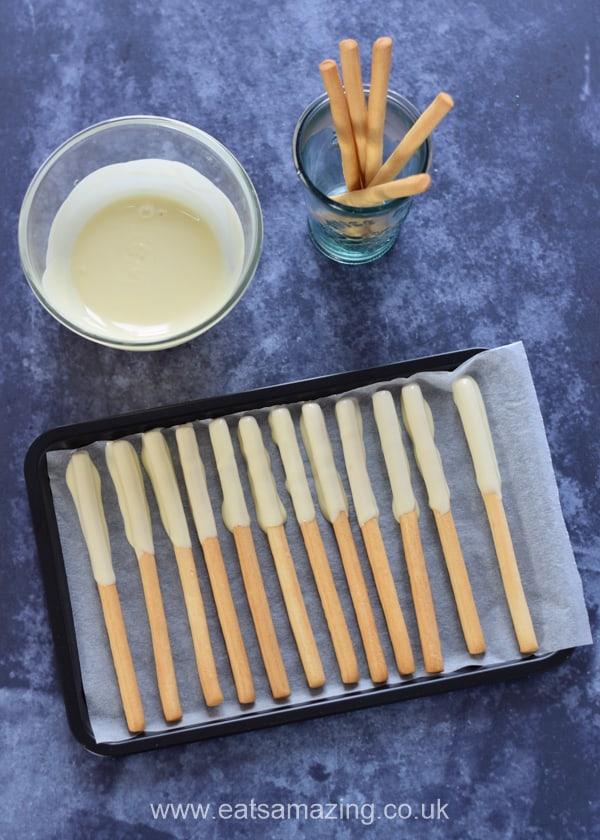 Edible Monster Breadstick Wands recipe - step 1 dip the breadsticks in melted white chocolate