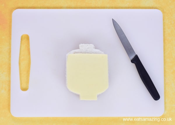 How to make an Emmet Lego man sandwich inspired by Lego Movie 2 - step 3 place the sandwich on top of a slice of cheese and cut around then pop the cheese on top
