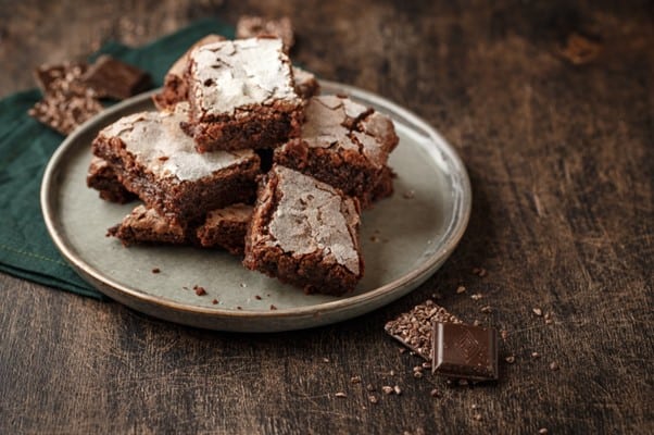 Pile of Chocolate Brownies on a grey plate set on a dark wood background